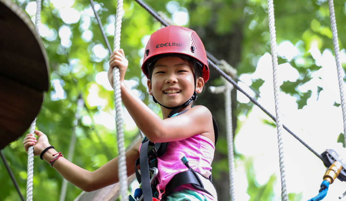 A camper climbing on the ropes course