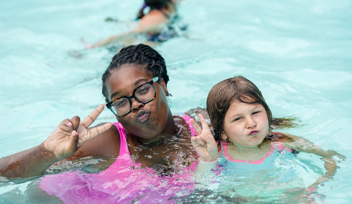 A camper and a counselor sharing a smile in the pool
