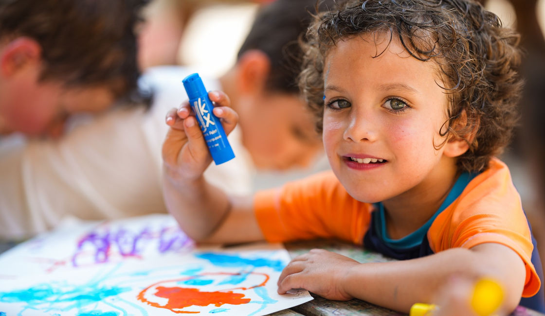A camper making colorful artwork at a table