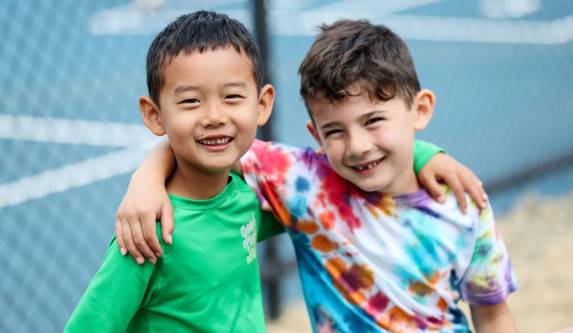 Two campers smiling with their arms around each other